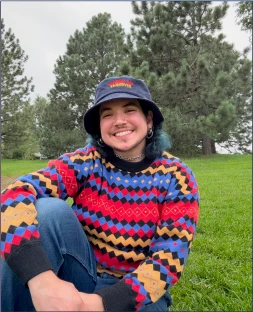 Greyson Casanova smiling outdoors in a colorful sweater and bucket hat